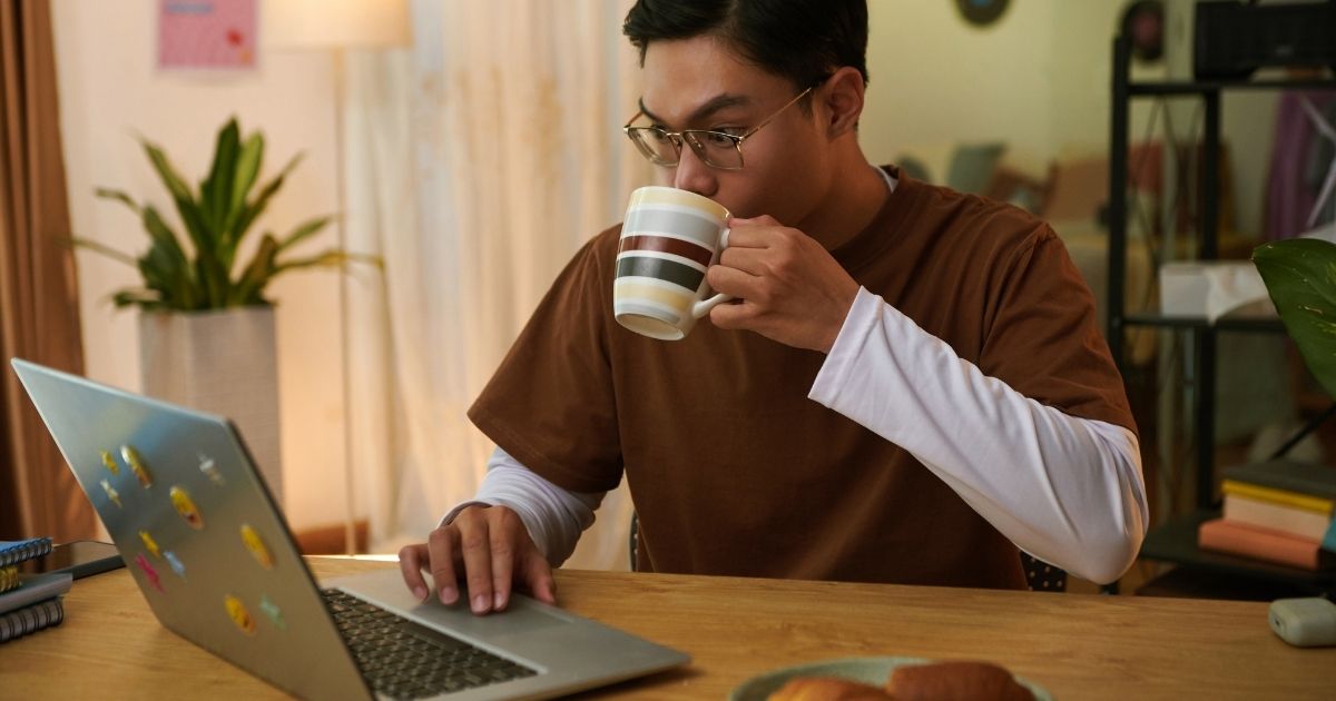 College student studying in a library with a cold brew coffee, laptop, and textbooks