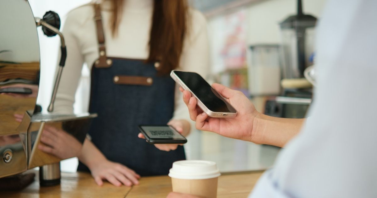 Person using a coffee recommendation app on their phone while standing in a café line